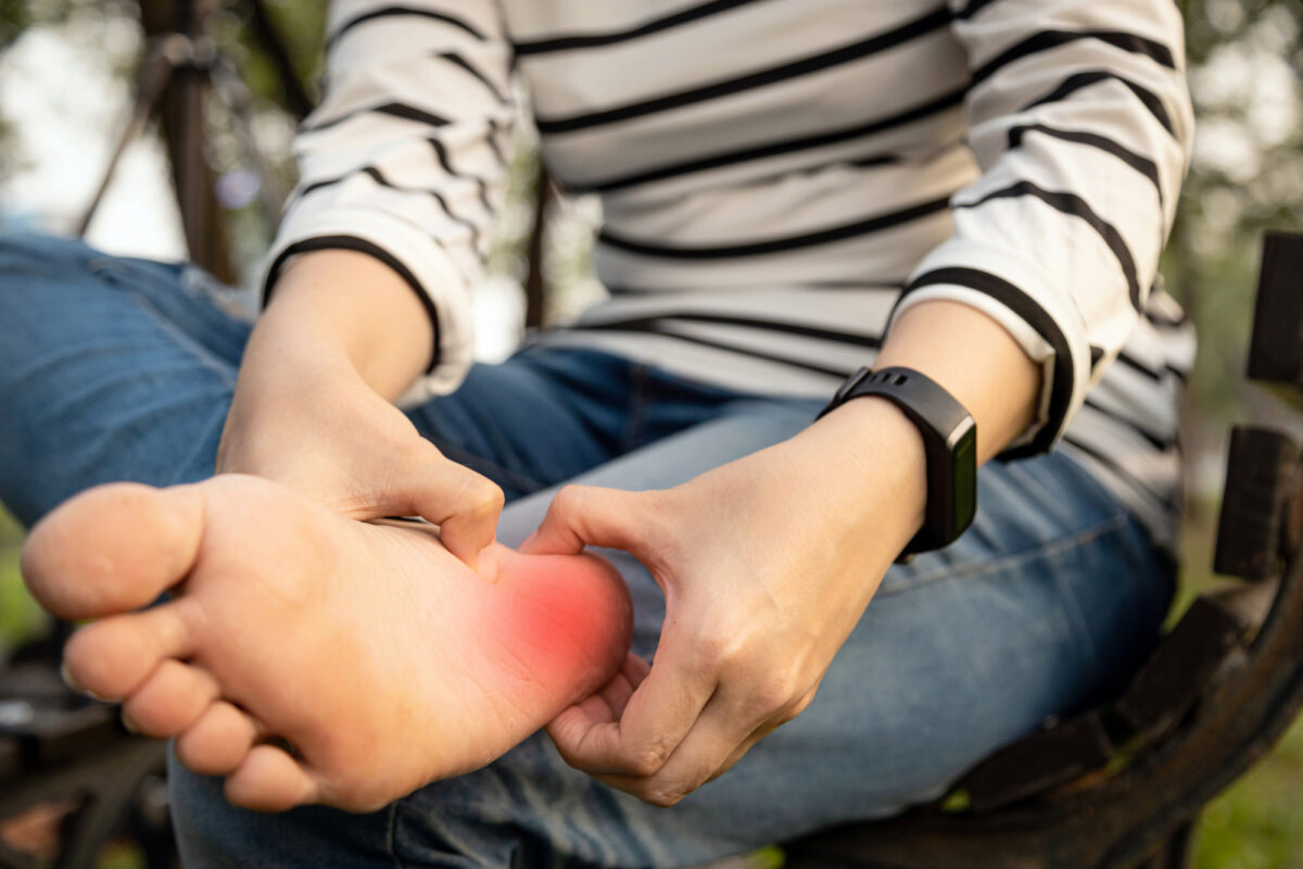 Young woman holding her feet and massaging heel with her hands.