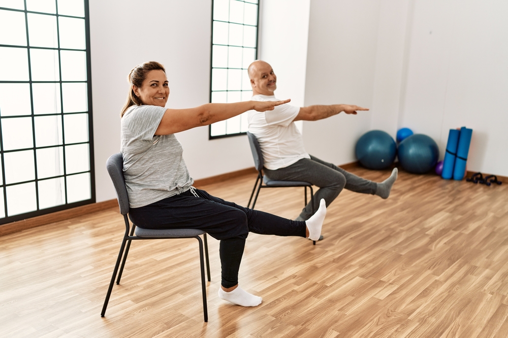 senior couple doing chair exercises for stronger core in studio