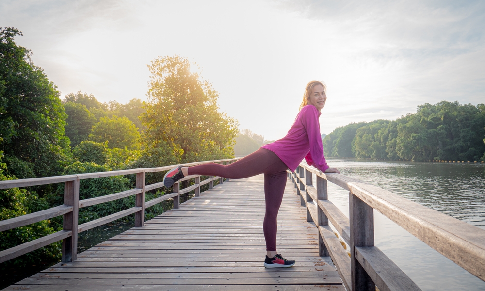 Woman stretching her legs on a bridge.