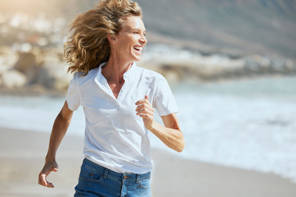 woman walking happy on beach in sunshine