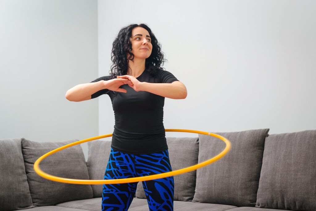 Woman rotating a weighted hula hoop. 