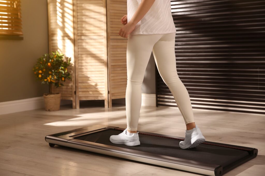 A woman walking on a walking pad in her home.