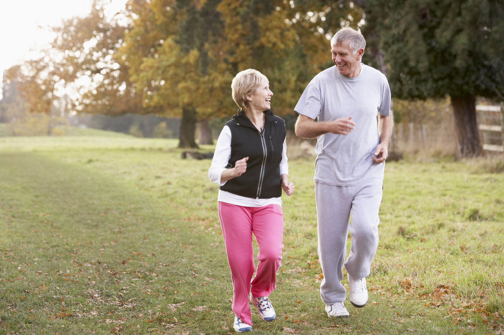 A senior couple power walking outdoors.