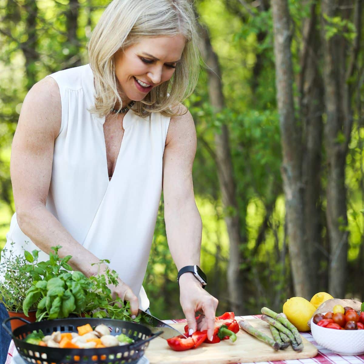 Chris Freytag chopping vegetables on a cutting board outside.