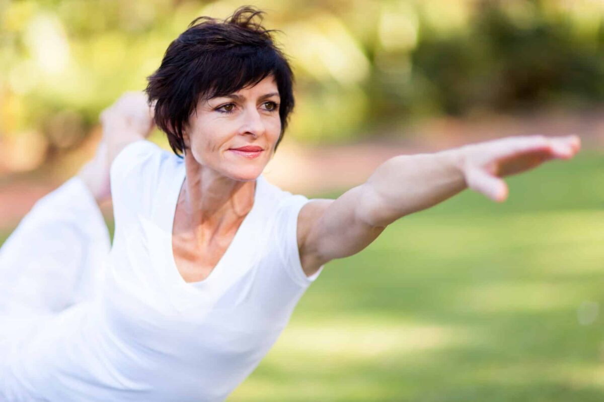 Older woman doing yoga outside.