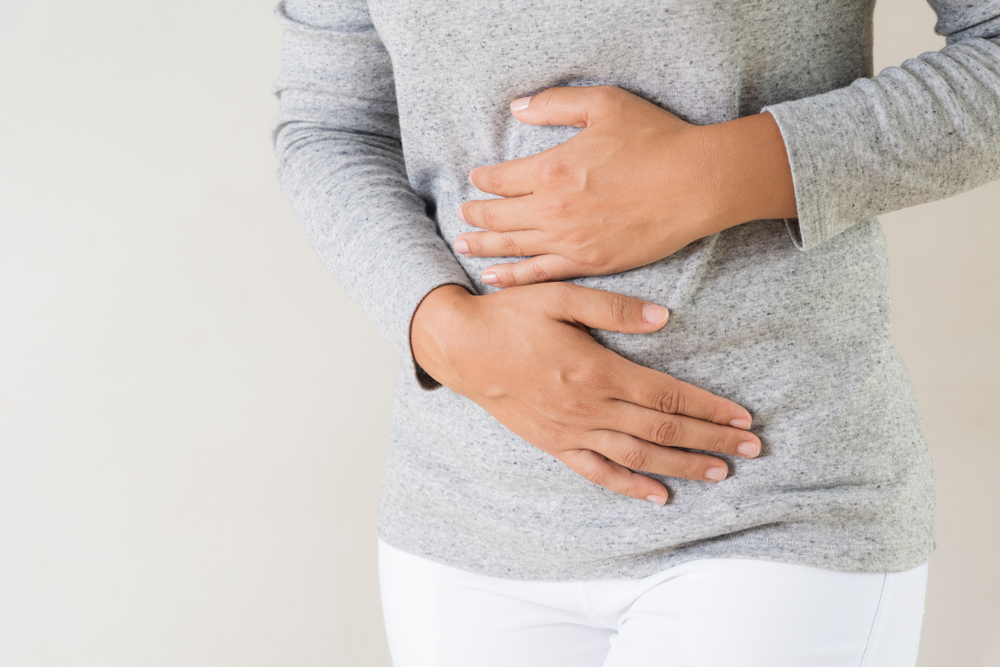 A woman with belly pain grabbing her abdomen.