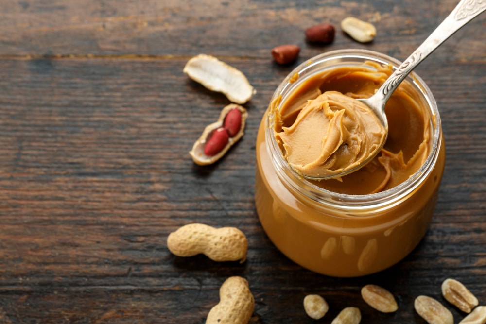 Top view of a spoon scooping peanut butter out of a jar.