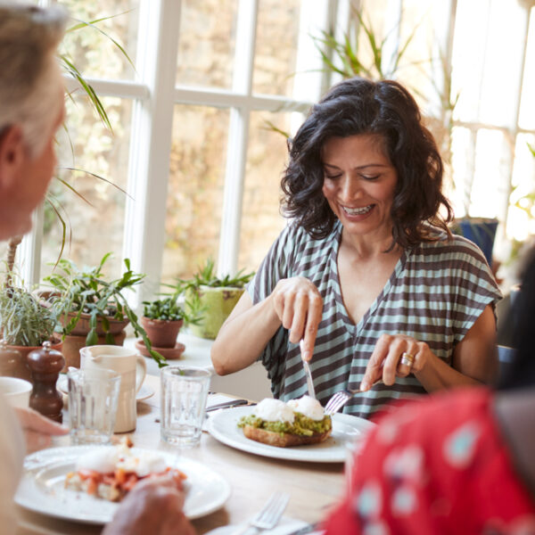 Woman eating a high protein breakfast in a cafe with friends.