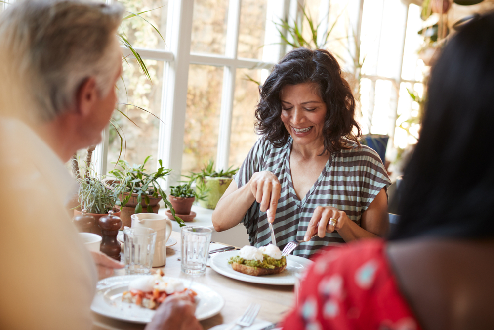 Woman eating a high protein breakfast in a cafe with friends.