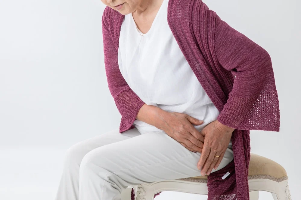 Older woman sitting in a chair with hip pain.