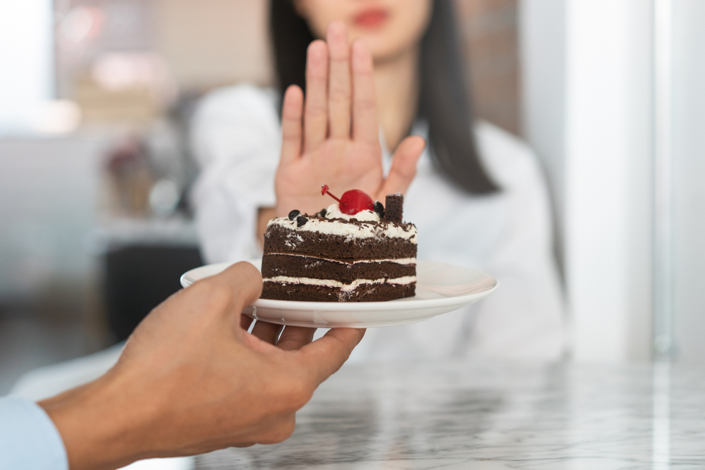 Woman refusing to eat cake.