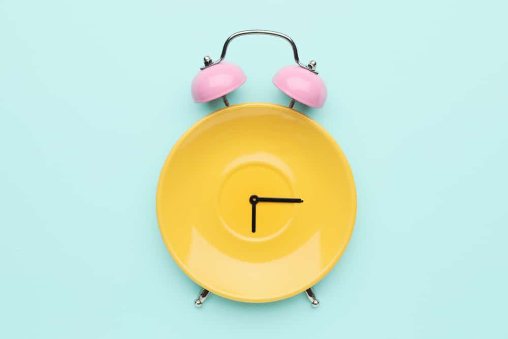 Clock hands and bells on a yellow plate.