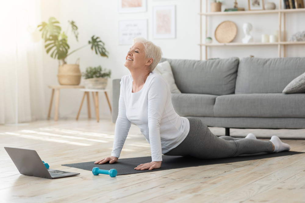 Senior woman doing yoga for back pain in her living room.