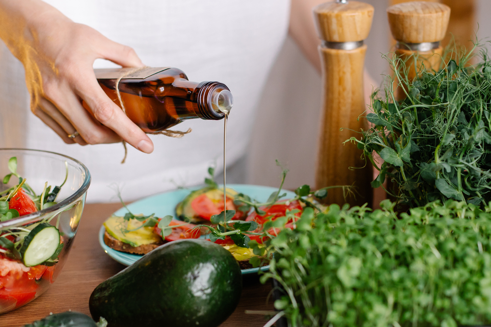 Woman pouring olive oil on a salad.