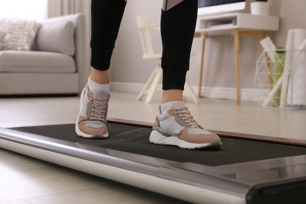 Woman training on walking pad at home.