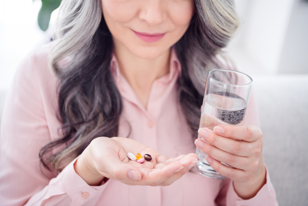 Close up of a woman taking medication with water.