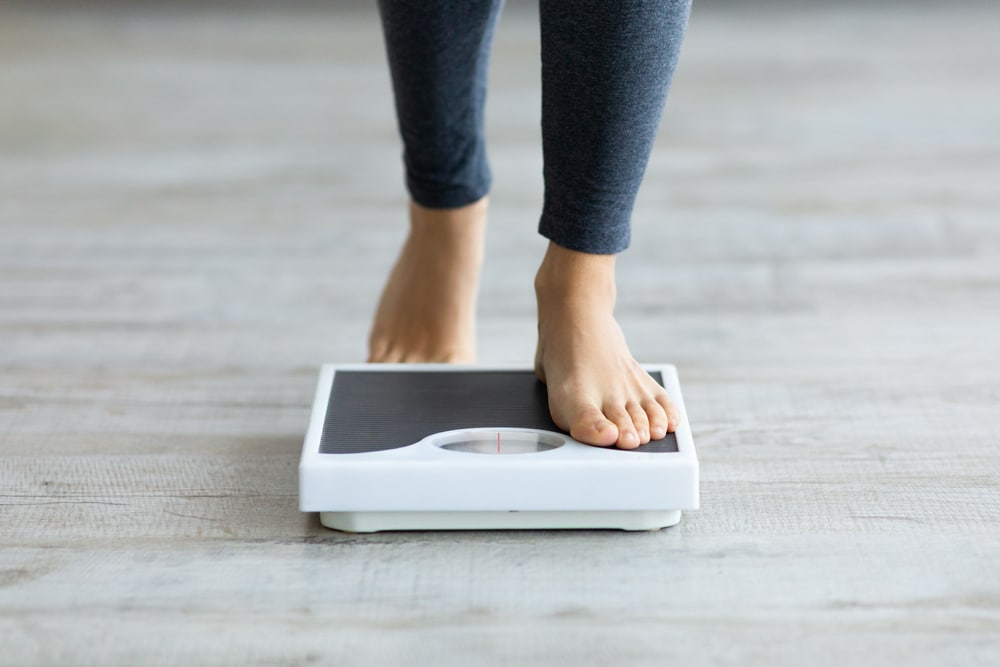 A person's feet stepping onto a floor scale.