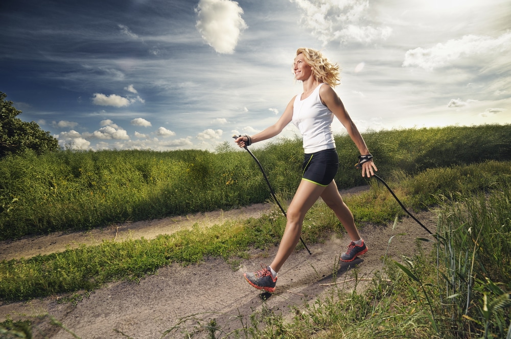 A woman power walking on an outdoor trail.