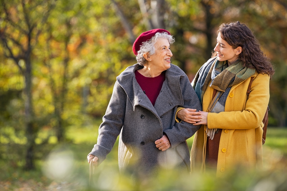 Young woman walking with a a senior woman in the park.