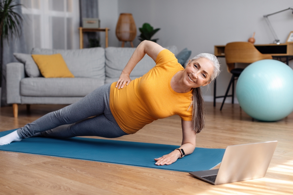 Senior woman doing a side plank exercise for getting rid of love handles.