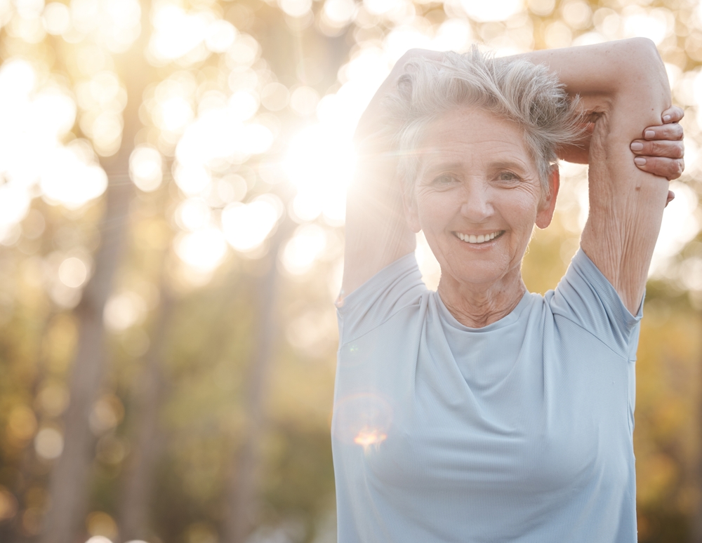 Senior woman doing mobility exercises outdoors.