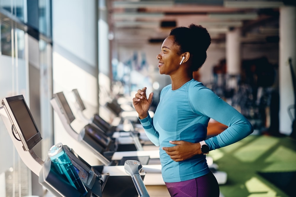 Happy woman running on a treadmill at the gym.