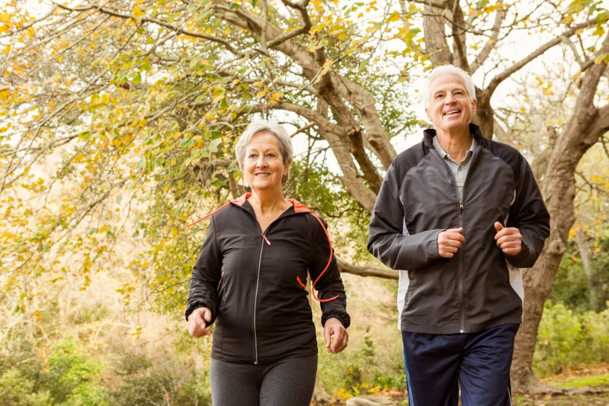 Senior couple in workout clothes walking in the park.