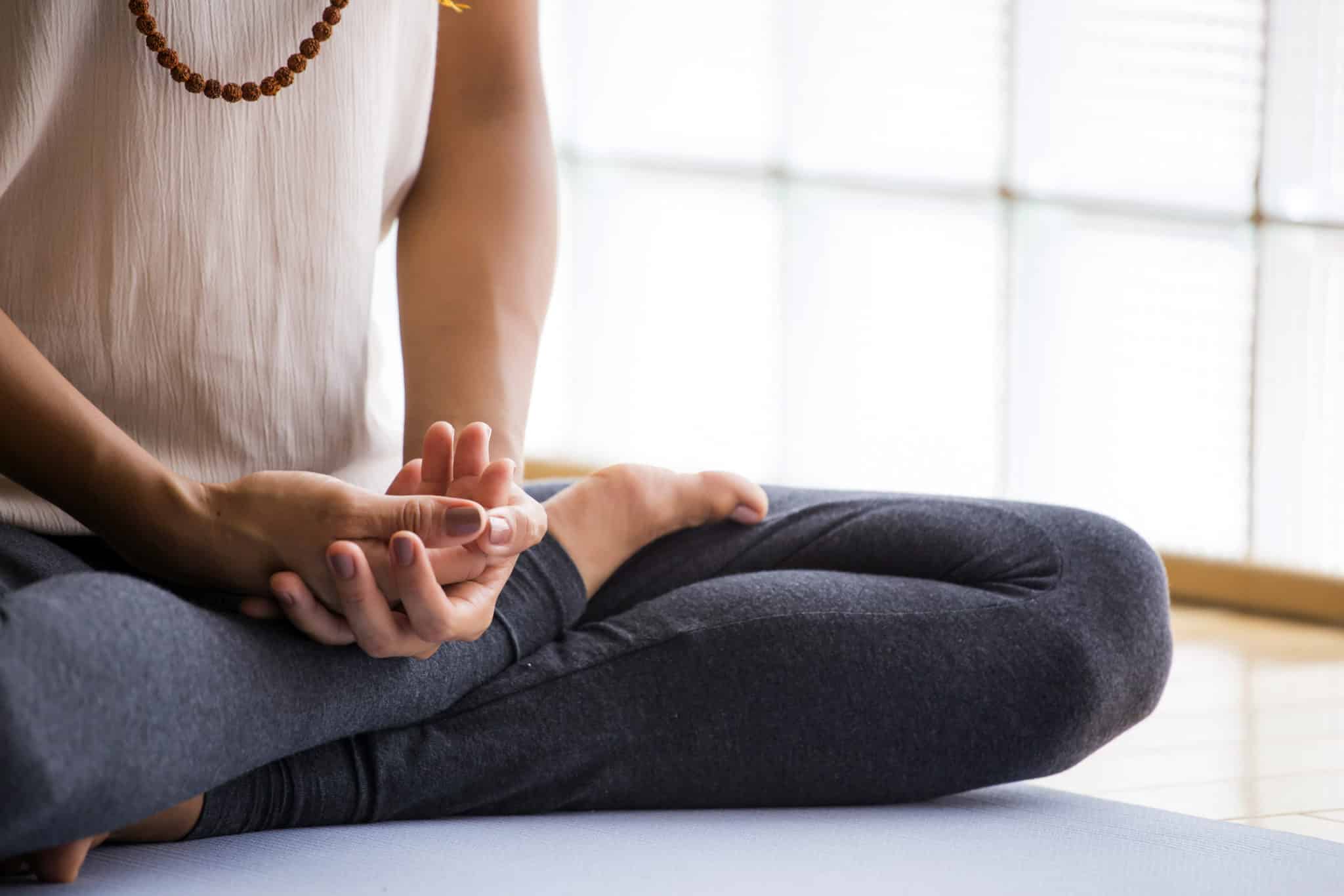 A woman sitting cross-legged with hands in lap for meditation.