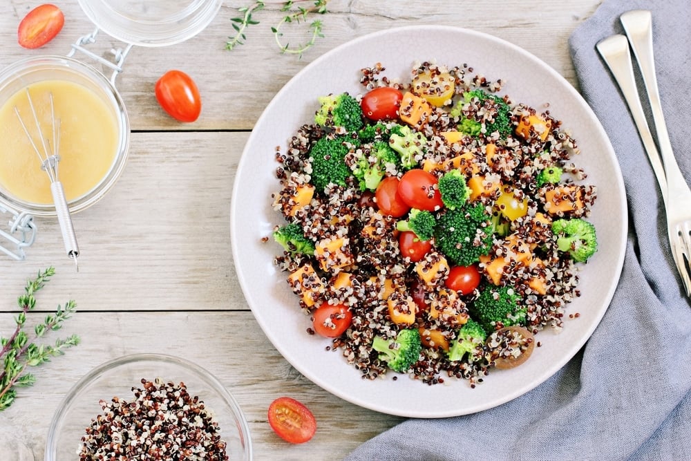 Top view of a bowl of quinoa topped with veggies and seeds.