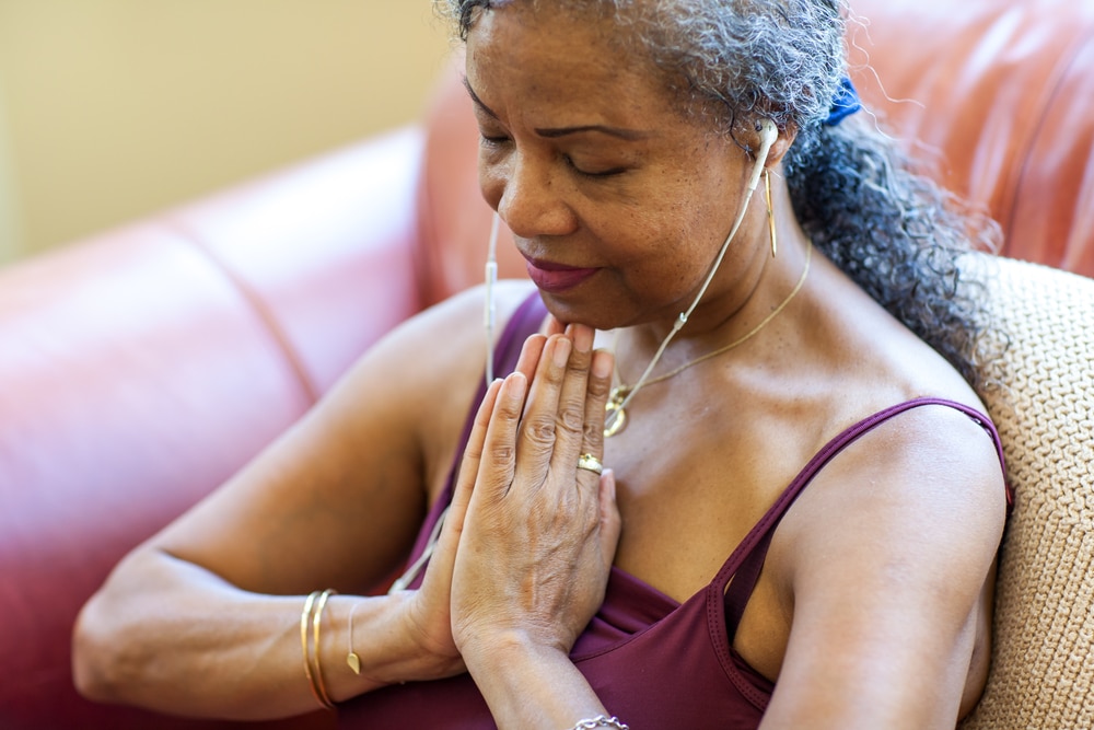 Senior woman meditating with her hands in a prayer position.