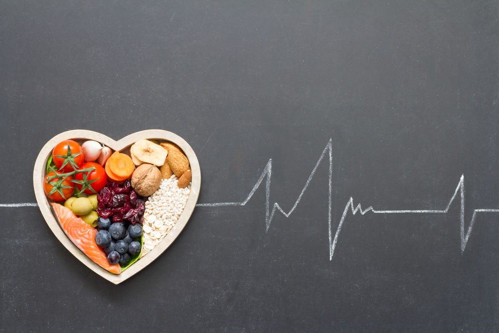 Healthy food in heart and cardiograph on blackboard.