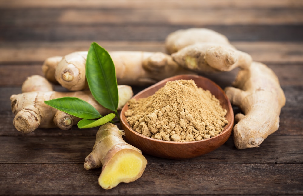 Ginger root next to ginger powder in a bowl.