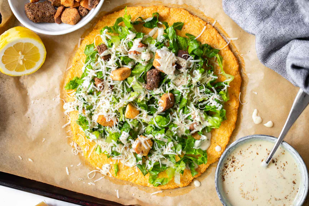 Top view of the viral chicken Ceasar salad pizza on a sheet pan.