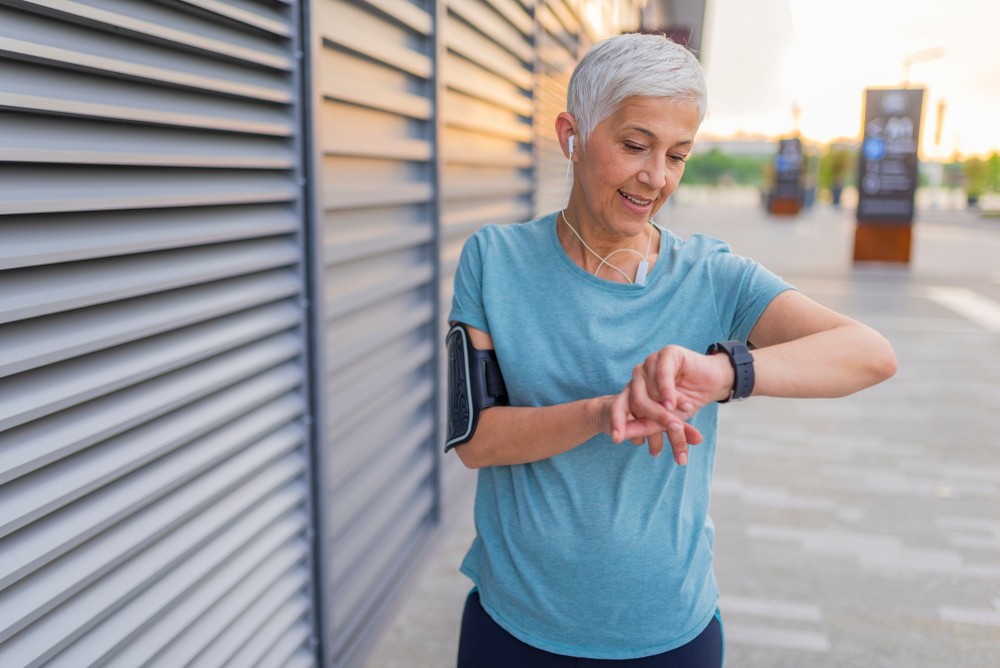 A woman monitoring her running performance on a smart watch using a fitness tracker.