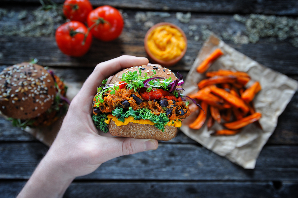 A hand holding a veggie black bean burger.