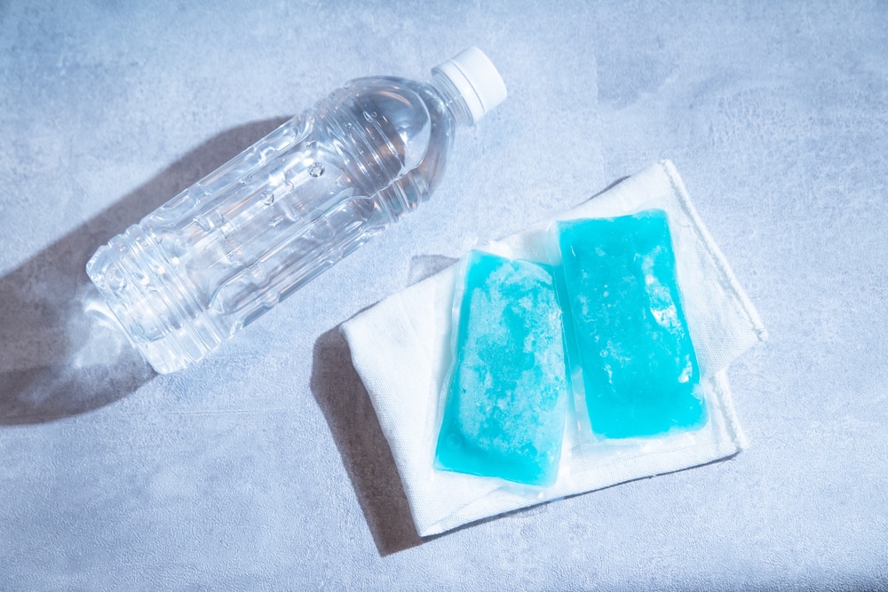 A water bottle laying next to two blue ice packs.