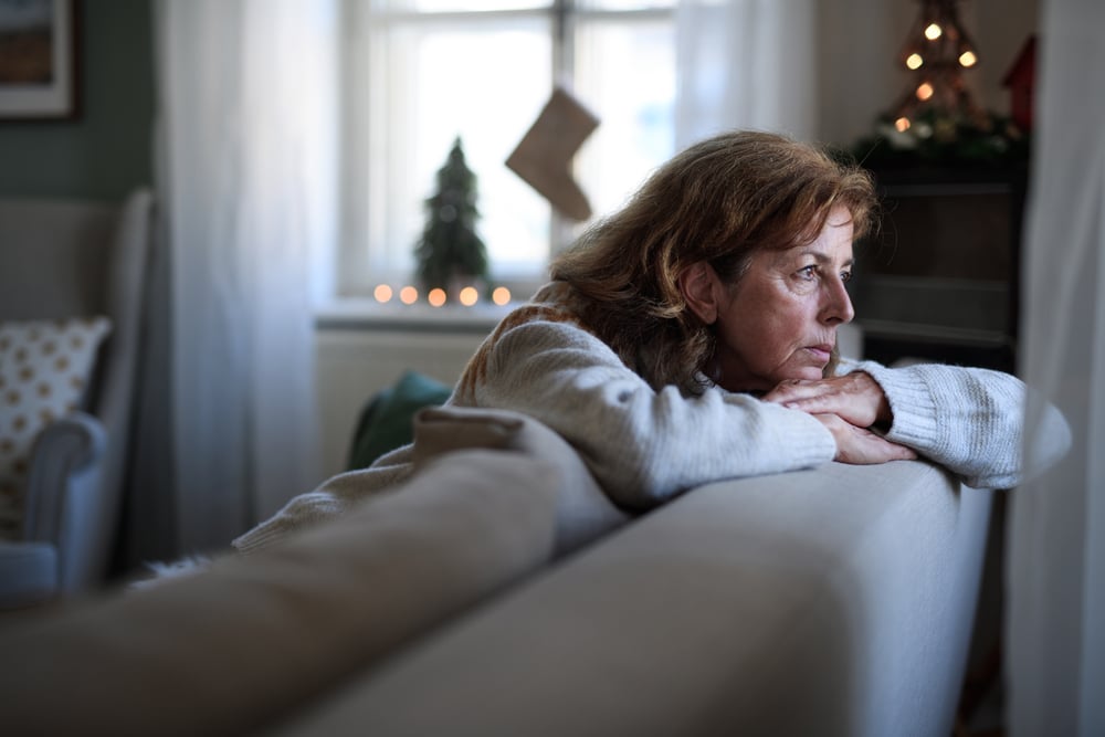 A sad woman feeling lonely while sitting on her couch.