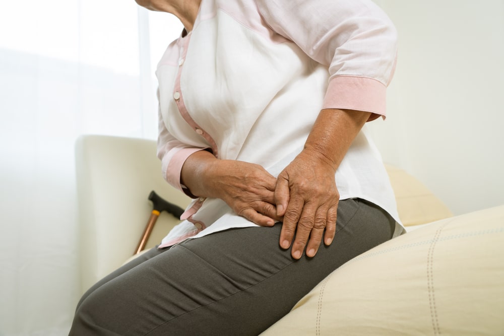 A woman sitting on the bed with hip joint pain.