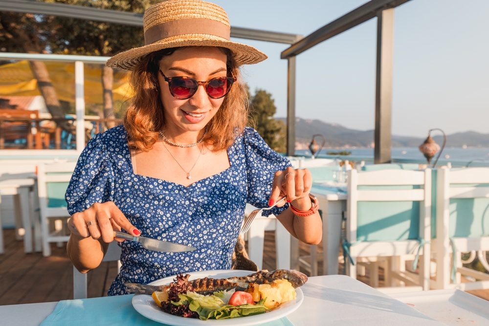 A woman eating a Mediterranean diet dish outdoors.