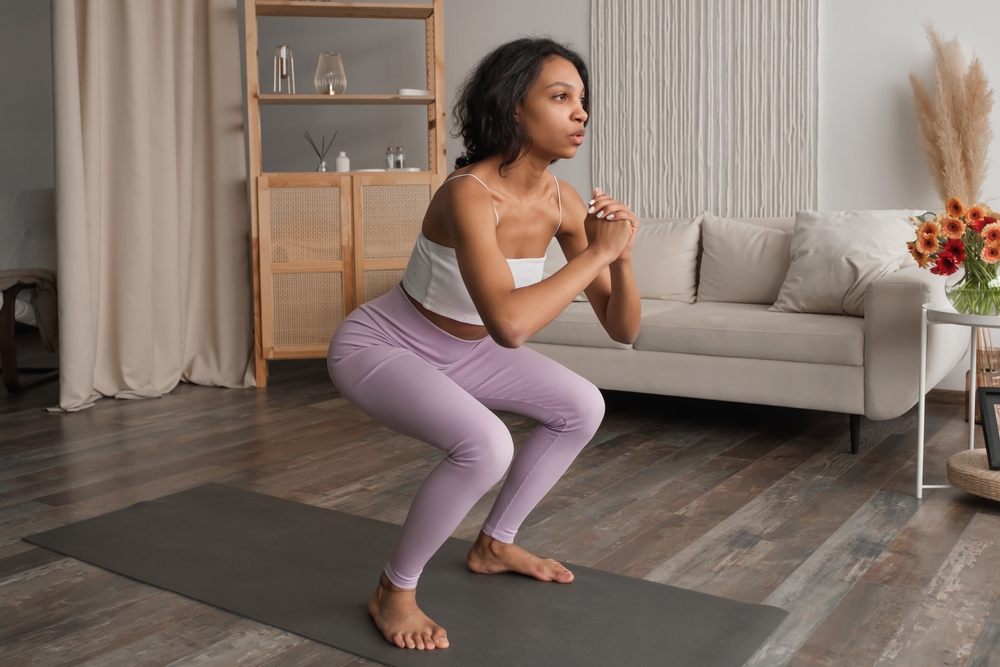 Side view on fit woman doing squats at home.