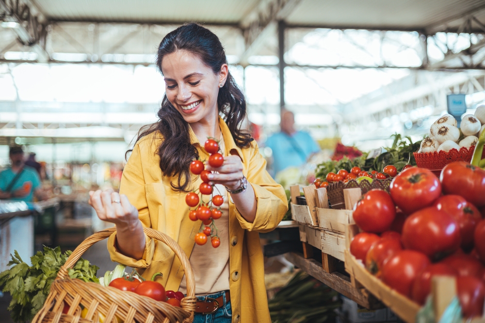 A smiling woman buying fresh tomatoes.