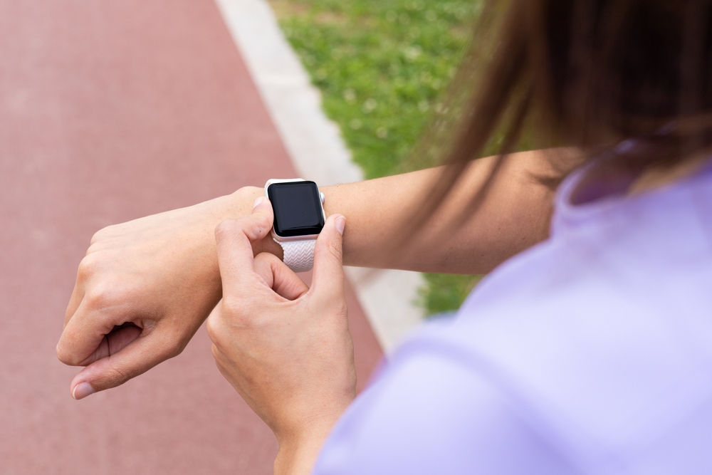 woman checking smartwatch fitness tracker after running outdoors.