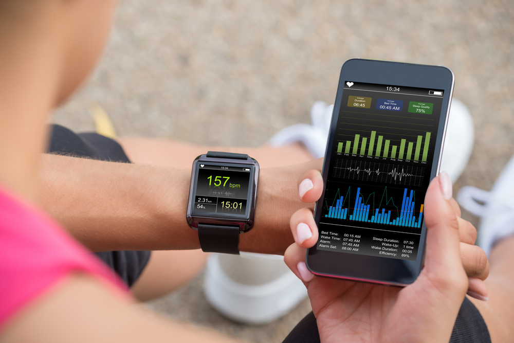 Female Runner Looking At Her Mobile And Smart Watch fitness tracker.