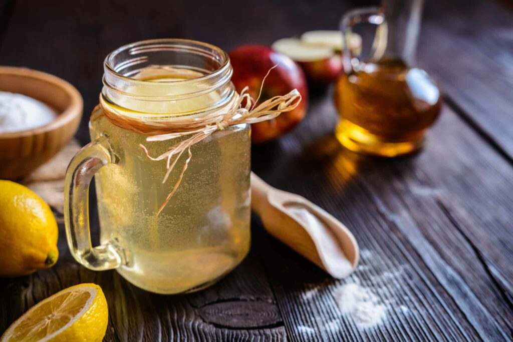 A mason jar of apple cider vinegar on a wooden table.