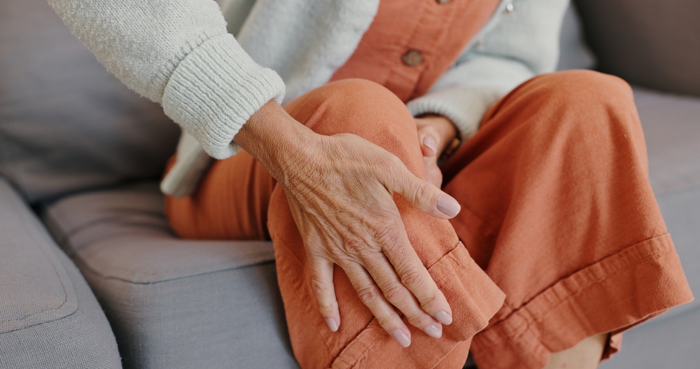 Closeup of a senior woman holding her knee in pain from osteoporosis.