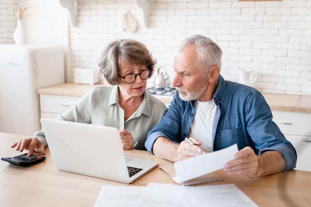 couple confused working on computer in kitchen