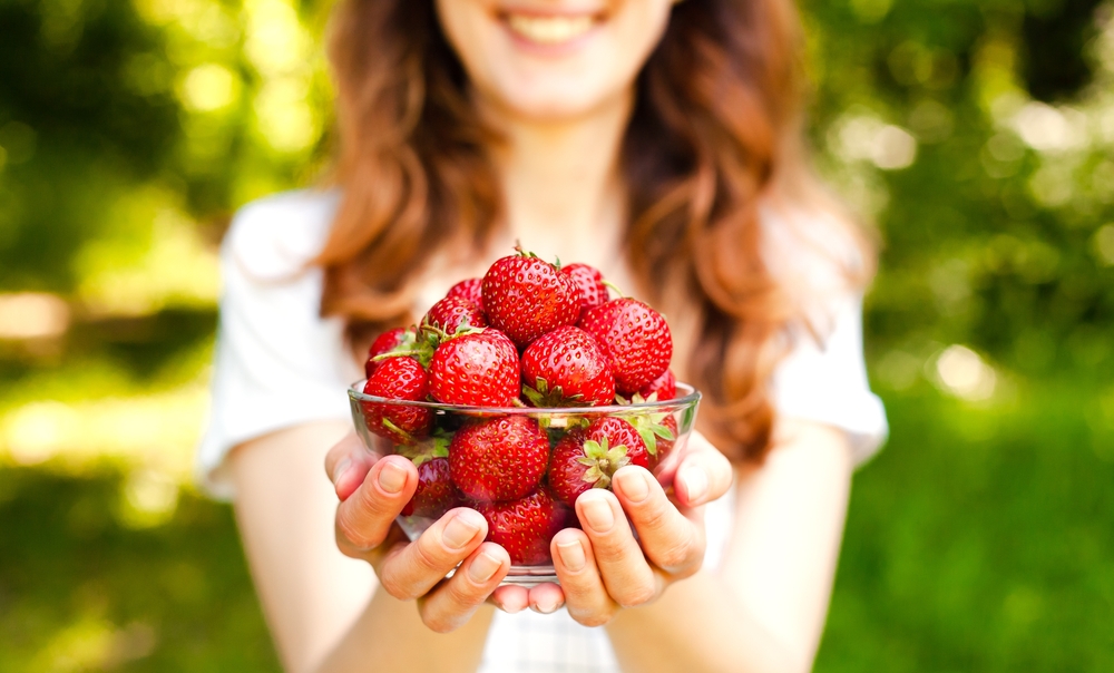 foods that lower blood pressure woman holding strawberries